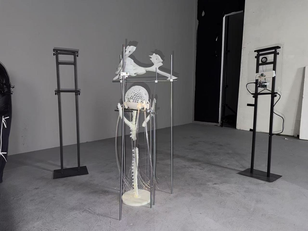 The installation standing in a gray studio between two tall stands, partly assembled.