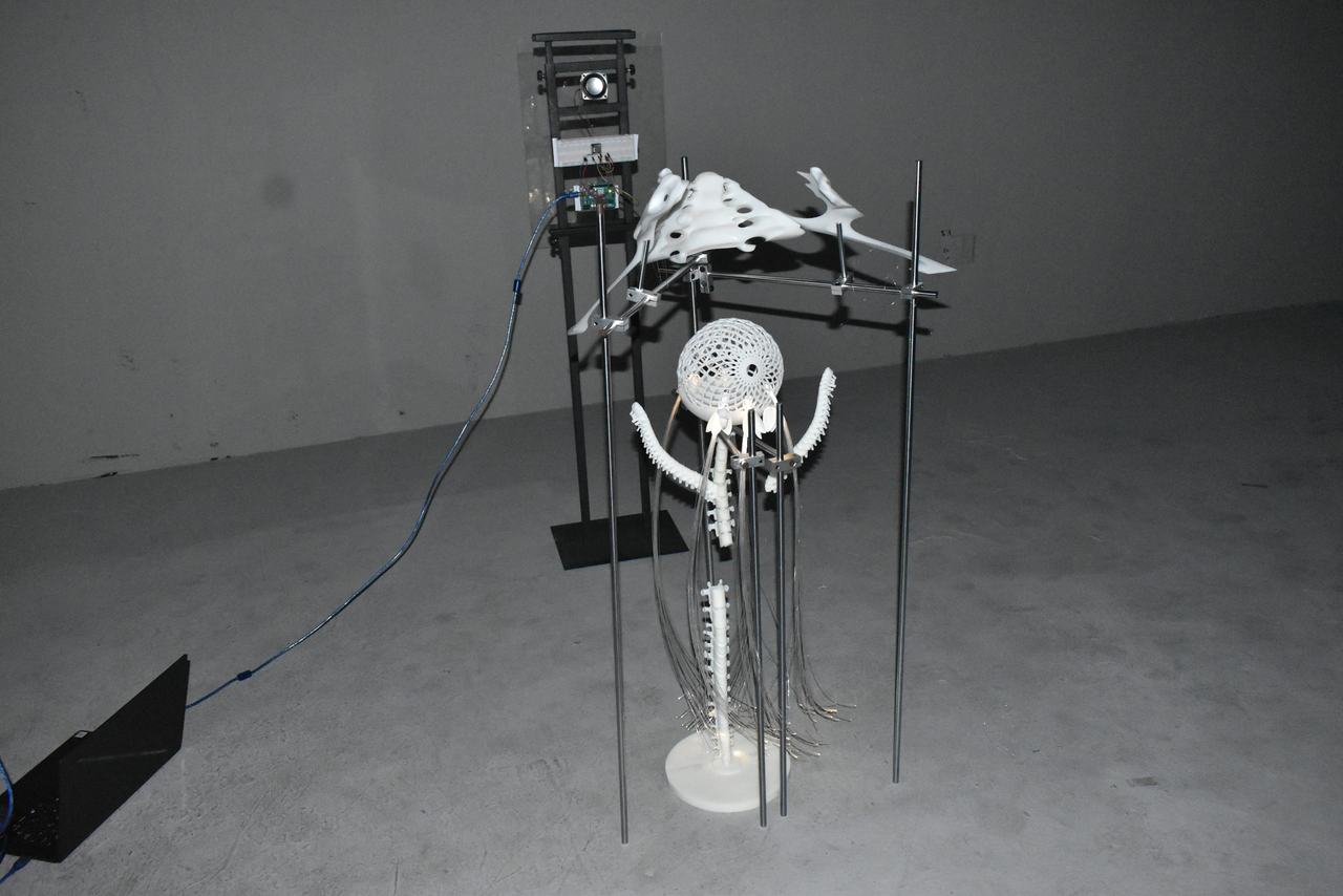The installation seen at an angle, its cables running across the floor to a laptop.